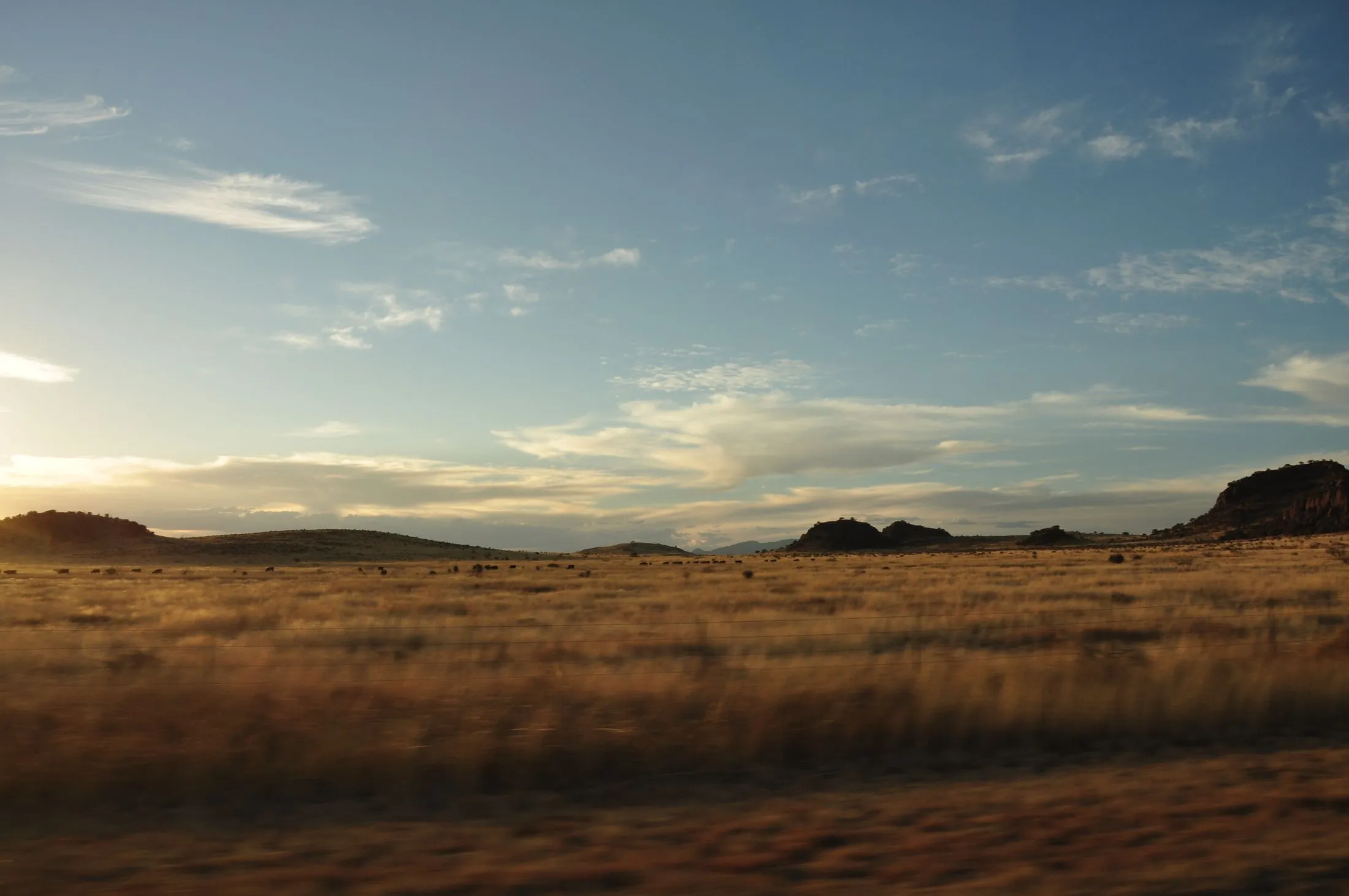 Golden grassland and low hills at sunset under a wide Texas sky
