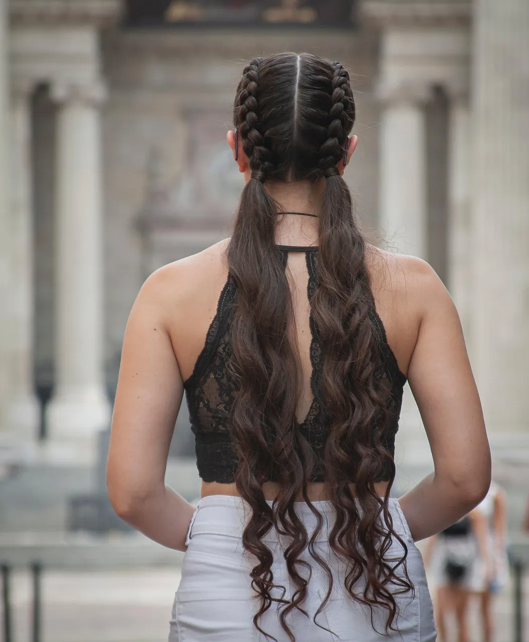 Two braids that open into long brown waves, seen from behind