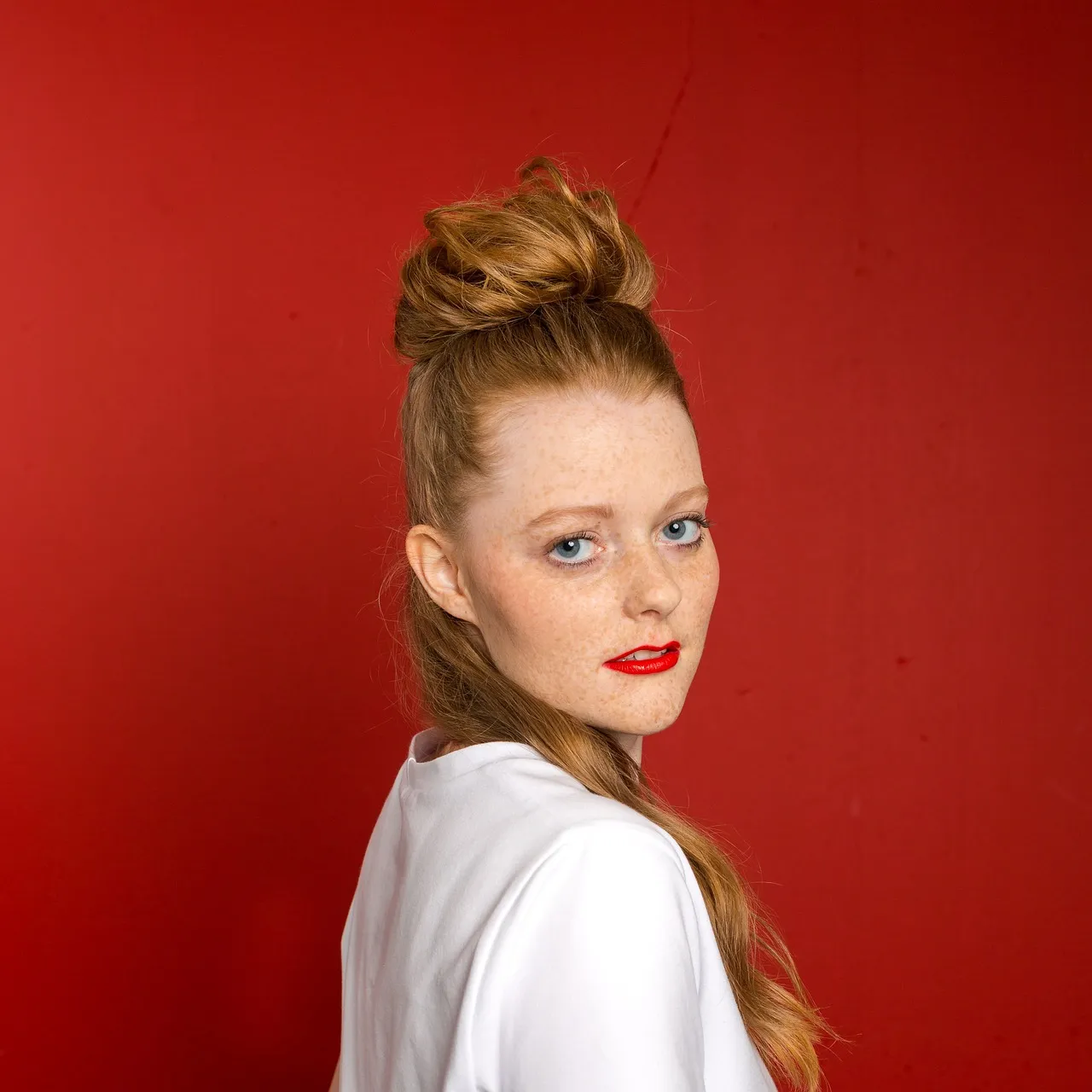 A high, loose bun with face-framing pieces on strawberry blonde hair