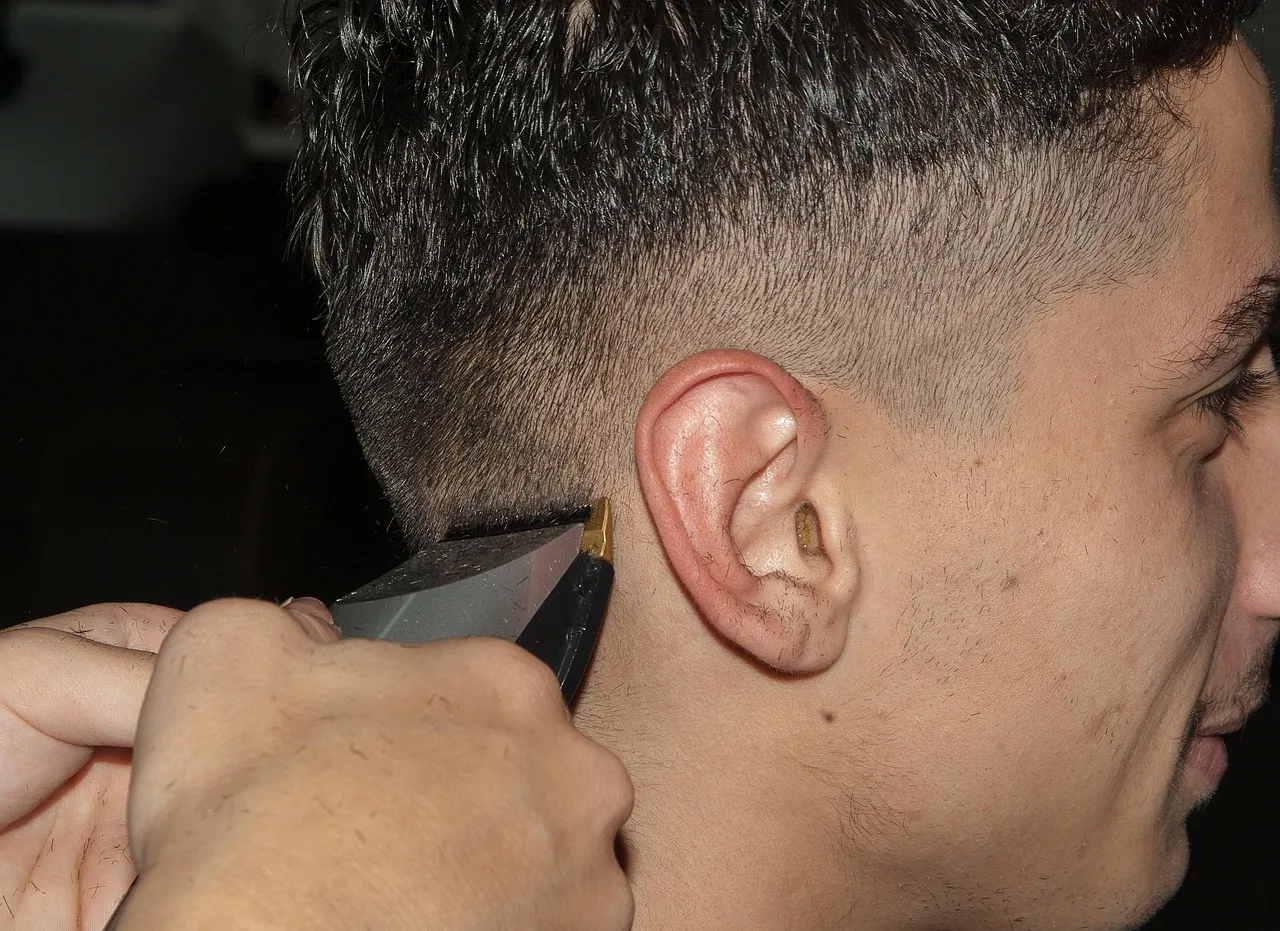 Close-up of a trimmer cleaning up the hairline around a client's ear