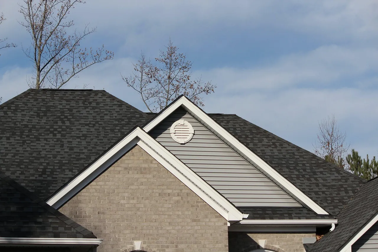 A brick house with a dark architectural-shingle roof under a clearing sky