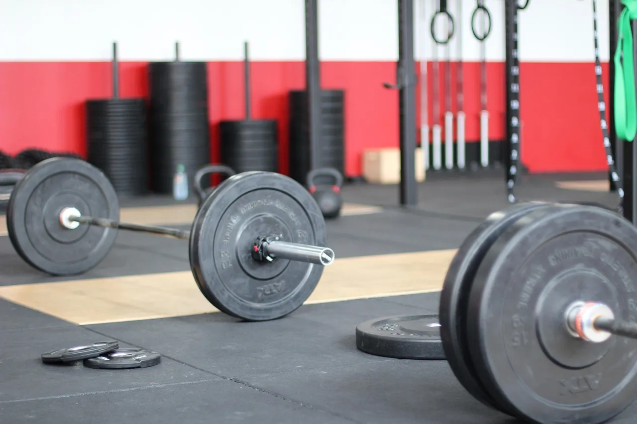 Barbells loaded with bumper plates on lifting platforms in front of a rack of plates