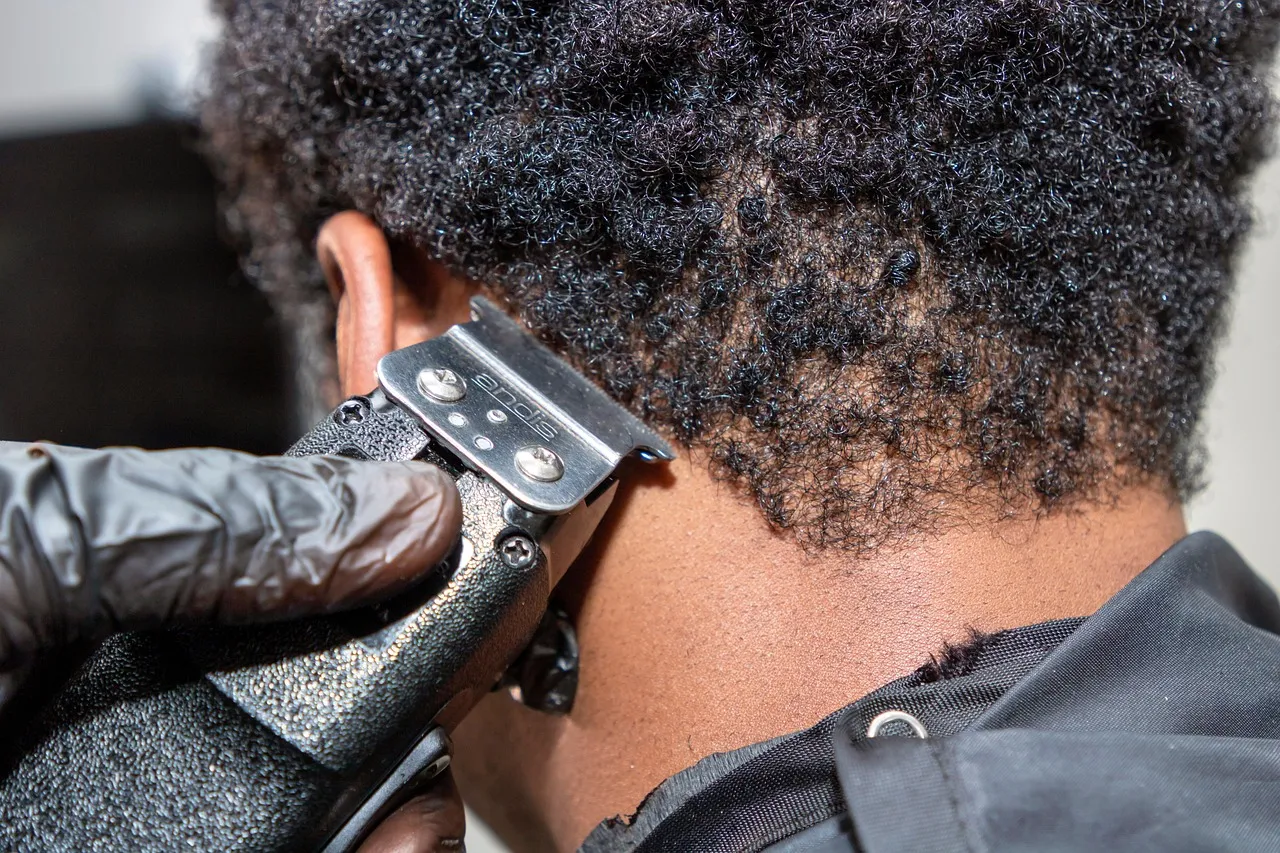 Clippers tapering the nape under curly hair