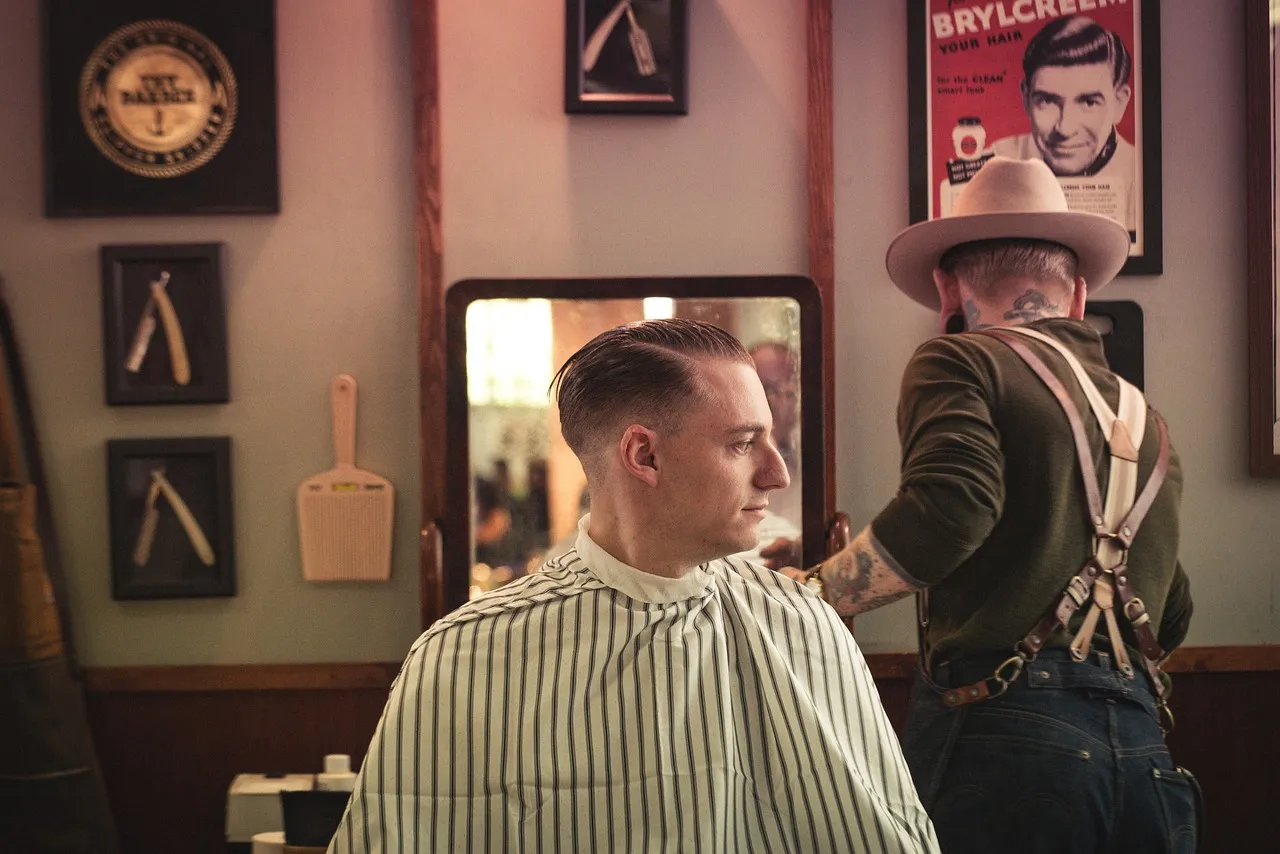 A client in a striped cape with a fresh side part, checking it in the mirror