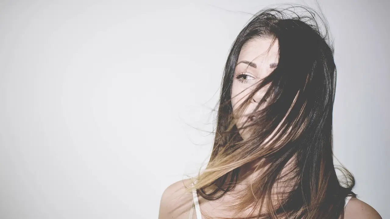 Long dark hair fading to lighter ends, moving across the face